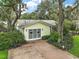 A yellow siding garage featuring carriage doors and brick paving surrounded by manicured shrubbery and mature trees at 24 Brigadoon Cir, Leesburg, FL 34788