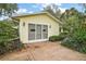 View of the detached garage with brick paving and carriage doors, with mature trees and shrubbery at 24 Brigadoon Cir, Leesburg, FL 34788