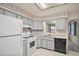 Charming kitchen featuring gray cabinets, white appliances, and a double basin sink at 24 Brigadoon Cir, Leesburg, FL 34788