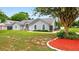 Single-story home featuring arched windows, a well-maintained lawn, mature landscaping, and shade trees at 2705 Bayview Dr, Eustis, FL 32726