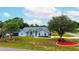 Charming single-story home with well-manicured lawn, mature trees, a blue exterior, and architectural windows at 2705 Bayview Dr, Eustis, FL 32726