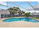 Beautiful screened-in pool with a clear blue water and lush landscaping in the background at 2705 Bayview Dr, Eustis, FL 32726