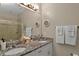 Modern bathroom with double granite vanity top, two sinks, a large mirror, and neutral-toned walls at 27121 White Plains Way, Leesburg, FL 34748