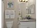 View of a sink with a decorative mirror, towels, and a toilet in a bathroom with neutral paint at 27121 White Plains Way, Leesburg, FL 34748