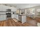 Open kitchen flows into dining area with stainless appliances, granite counters, and hardwood floors for a seamless design at 27121 White Plains Way, Leesburg, FL 34748