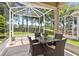 Enclosed lanai with a table set and seating overlooking a lush green landscape at 27121 White Plains Way, Leesburg, FL 34748