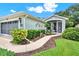 Well-maintained home with manicured shrubs, mulch beds, and winding concrete pathway at 27302 Stoney Brook Dr, Leesburg, FL 34748