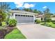 Exterior view of a home's two-car garage, landscaped yard, and well-kept lawn at 27302 Stoney Brook Dr, Leesburg, FL 34748