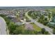 An aerial view shows this beige home near a manicured traffic circle with mature palm trees at 2954 Heiny Pl, The Villages, FL 32163