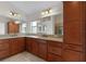 Bathroom with wood cabinets, granite countertop, and large mirrors offering plenty of light and storage at 2954 Heiny Pl, The Villages, FL 32163
