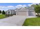 One-story home featuring a three-car garage, beautiful landscaping, and a lush green lawn at 2954 Heiny Pl, The Villages, FL 32163