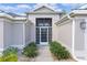 Inviting front entrance with a decorative white security door, lush landscaping, and charming curb appeal at 2954 Heiny Pl, The Villages, FL 32163