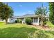 Well-maintained backyard featuring lush green grass, mature trees, and a charming screened lanai at 2991 Saint Thomas Ln, The Villages, FL 32162