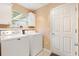 Laundry room featuring a washer, dryer, storage cabinets, and access door at 2991 Saint Thomas Ln, The Villages, FL 32162