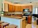 Open concept kitchen with stainless appliances, wood cabinets, and breakfast bar at 30604 Apawamis Dr, Sorrento, FL 32776