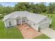 An aerial view of a one story, gray home with great curb appeal with a brick driveway and manicured lawn at 316 Dupont Cir, Howey In The Hills, FL 34737
