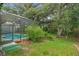 Backyard features a screened pool area, lush lawn, and mature trees, offering privacy at 32948 Rambling Oaks Ct, Leesburg, FL 34748