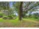 Landscaped backyard with lush plants, a mature tree, and a view of the screened-in pool area at 32948 Rambling Oaks Ct, Leesburg, FL 34748