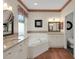 Bathroom featuring a jacuzzi tub, double sinks, wood look flooring, and floral wallpaper trim at 32948 Rambling Oaks Ct, Leesburg, FL 34748
