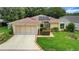 Charming single-story home featuring a well-kept lawn, mature landscaping, and attached garage at 32948 Rambling Oaks Ct, Leesburg, FL 34748