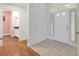 Bright foyer with neutral tile flooring and white front door, adjacent to a laundry room at 32948 Rambling Oaks Ct, Leesburg, FL 34748