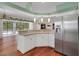 Kitchen features granite countertops, white cabinets, stainless steel refrigerator, and wood floors at 32948 Rambling Oaks Ct, Leesburg, FL 34748
