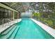 In-ground pool with screened enclosure and steps, surrounded by a concrete patio at 32948 Rambling Oaks Ct, Leesburg, FL 34748