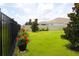 Lush backyard with a black metal fence, manicured lawn, and colorful flower planters at 33647 Sky Blossom Cir, Leesburg, FL 34788