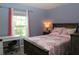 Cozy bedroom with a wooden bed frame, floral bedding, and a window with pink curtains at 33647 Sky Blossom Cir, Leesburg, FL 34788