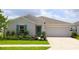 Charming single-story home features a well-manicured lawn, a two-car garage, and a decorative teal front door at 33647 Sky Blossom Cir, Leesburg, FL 34788