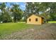 Exterior view of a detached yellow building on an expansive grassy lot with mature trees at 37236 Cherry Lake Rd, Fruitland Park, FL 34731