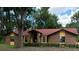Charming single-story home with brick facade, red roof, and manicured front yard landscaping at 37236 Cherry Lake Rd, Fruitland Park, FL 34731