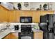 Bright kitchen features wood cabinets, black appliances and decorative shelving at 3819 Saint Emma Ct, Leesburg, FL 34748