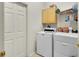 Compact laundry room features a washer, dryer, storage shelves, and a utility cabinet at 3819 Saint Emma Ct, Leesburg, FL 34748
