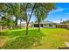 The spacious backyard features a lush lawn, mature trees, a privacy fence, and screened-in lanai at 39 Pine Court Dr, Ocala, FL 34472