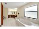 Bright bathroom featuring a marble-trimmed tub, dual vanities, and a large window for natural light at 39132 Grays Airport Rd, Lady Lake, FL 32159