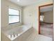 Elegant bathroom with a marble tub, a window for natural light, and access to the bedroom at 39132 Grays Airport Rd, Lady Lake, FL 32159