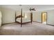 Spacious bedroom with a four-poster bed and neutral carpet, illuminated by a ceiling fan at 39132 Grays Airport Rd, Lady Lake, FL 32159