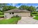 Beige home featuring a garage and well-maintained lawn, complemented by a long driveway, under a partly cloudy sky at 39132 Grays Airport Rd, Lady Lake, FL 32159