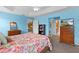 Bright bedroom includes bright blue walls, floral bedding, a ceiling fan, and ample natural light through windows at 3978 Nottingham Loop, The Villages, FL 32163