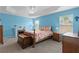 A beautiful bedroom with a floral bedspread, matching bedside tables, a ceiling fan and recessed lighting, and bright blue walls at 3978 Nottingham Loop, The Villages, FL 32163
