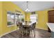 Bright dining area features a wooden table, upholstered chairs, yellow walls, and large windows that let in natural light at 3978 Nottingham Loop, The Villages, FL 32163