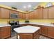 This yellow kitchen features stainless steel appliances, wood cabinetry, white countertops, and a functional kitchen island at 3978 Nottingham Loop, The Villages, FL 32163