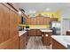 Bright kitchen with stainless steel appliances, wood cabinetry and flooring, white countertops, and an island with a fire extinguisher at 3978 Nottingham Loop, The Villages, FL 32163