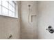 Modern tiled walk-in shower with a glass block window offers a clean and bright space with convenient shower features at 3978 Nottingham Loop, The Villages, FL 32163