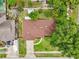 Overhead aerial view of a home with a brown roof, manicured lawn, driveway, and surrounding greenery at 400 W Washington St, Minneola, FL 34715