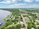 Expansive aerial view of the neighborhood, lush greenery, and waterfront homes lining the tranquil lake under a partly cloudy sky at 400 W Washington St, Minneola, FL 34715