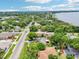 A high aerial view shows surrounding neighborhood homes and the lakefront home with mature trees and landscaping at 400 W Washington St, Minneola, FL 34715