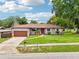 Inviting single-story home with stone details, a brown roof, and a manicured lawn at 400 W Washington St, Minneola, FL 34715