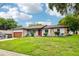 Attractive single-story home featuring stone accents, a red door, and a well-maintained front lawn at 400 W Washington St, Minneola, FL 34715